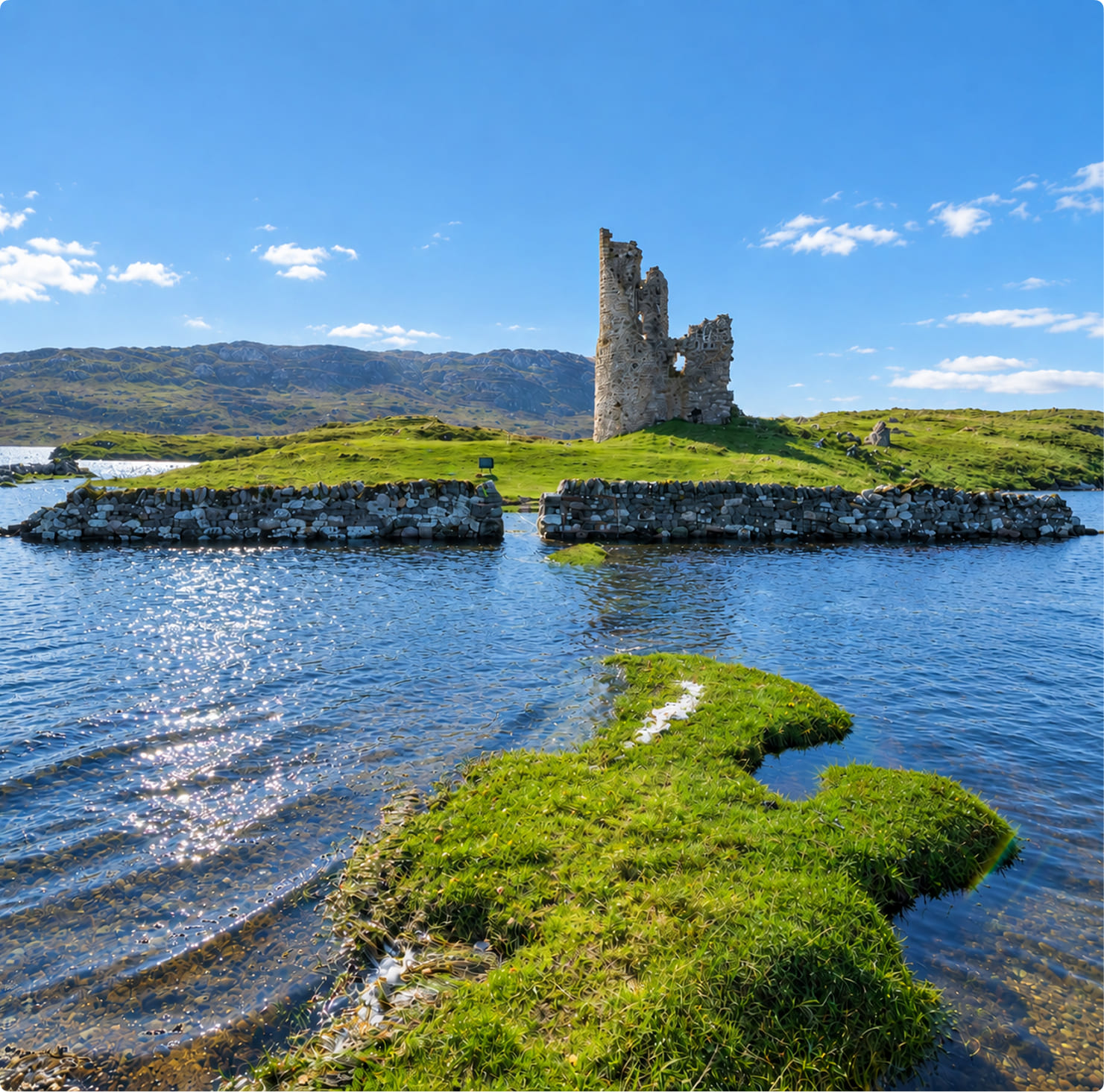Ruined tower of Ardvreck Castle on a grassy peninsula in Loch Assynt in the Scottish Highlands