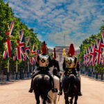 Mounted Household Cavalry riding down The Mall toward Buckingham Palace, lined with Union Jack flags