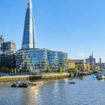 The Shard and modern glass buildings along the River Thames South Bank in London, with HMS Belfast moored nearby