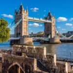 Tower Bridge over the River Thames on a sunny day, seen from the stone walls of the Tower of London