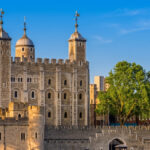 The White Tower and stone walls of the Tower of London in warm evening light