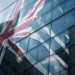 Union Jack flag reflected in the glass facade of a modern office building